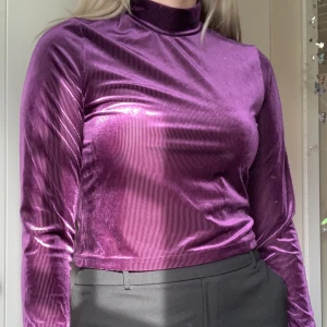 Lila Croppad Turtleneck - Tyget är en blandning mellan manchester och sammet. Inte jätte stretchig men man kan ändå röra sig bekvämt i den.