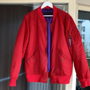 Bomberjacka  - Röd jacka som är lila på insidan. Ett hål vid ena ärmen, annars bra skick. Nypris cirka 1500 kronor.