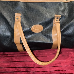 Weekend bag i skinn från Colling - Superfin och stor weekend bag från Collings.  Ett innerfack finns.  Axelband finns ej. Färg: svart skinn med bruna band.   Ej använd. 