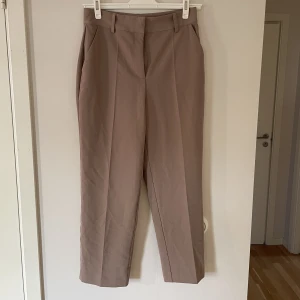 Kostymbyxor - Croppade kostymbyxor, färg: bindning mellan rosa, beige och grå, aldrig använda, lapp kvar, smala i midjan, säljer pga kommer ej till användning