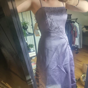 Lila balklänning  - En lila balklänning i storlek 5/6 från USA. Den har fina broderidetaljer och kommer med extra pärlor. Skulle säga att den är storlek 36-38, ca 130 cm lång från framsida ner. Den är oanvänd (har fortfarande lappen kvar). 