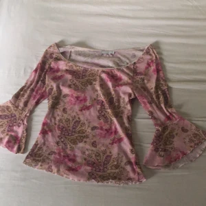 Off-shoulder witchy top - Rosa off shoulder topp med trumpetärm och paisly mönster. I gott skick och otroligt stretchig så kan passa större storlekar över M/L. Bystmått: minst 48x2. Midja: minst 84cm. Finns inga bilder på men Dma gärna vid andra frågor:) köparen står för frakt.