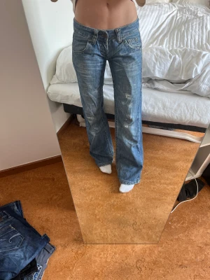 Lågmidjade jeans - Lågmidjade jeans, midjemått ca 41-42cm men jag har satt in ett snöre i midjan (som går att ta ut) skriv för bild! Innerbenslängden är ca 81,5cm. Är lite slitna vid hälarna vilket syns på bild 2