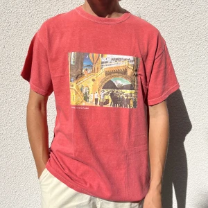 T-shirt med tryck - Röd t-shirt med snyggt tryck på framsidan från Urban Outfitters. Oversized passform, inga defekter och sparsamt använd. Perfekt till sommaren! Storlek S men modellen är M och det passar fint! Unisex.