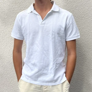 Pikétröja från J.Lindeberg - Kortärmad herrtenniströja från J.Lindeberg i storlek M. Superfin krämvit, gjord av 100% bomull! Liten defekt då märket på bröstet flagnat, men det syns knappt (se tredje bilden). Nypris ca 500 kr.