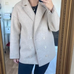 Kort kappa från NA-KD - Kort snygg kappa i beige från NA-KD, kollektionen afjxnakd. Finns inte längre kvar, nypris 800kr men säljer för 300kr, Storlek 36.  Skriv vid frågor💕 (Köparen står för frakten💗)