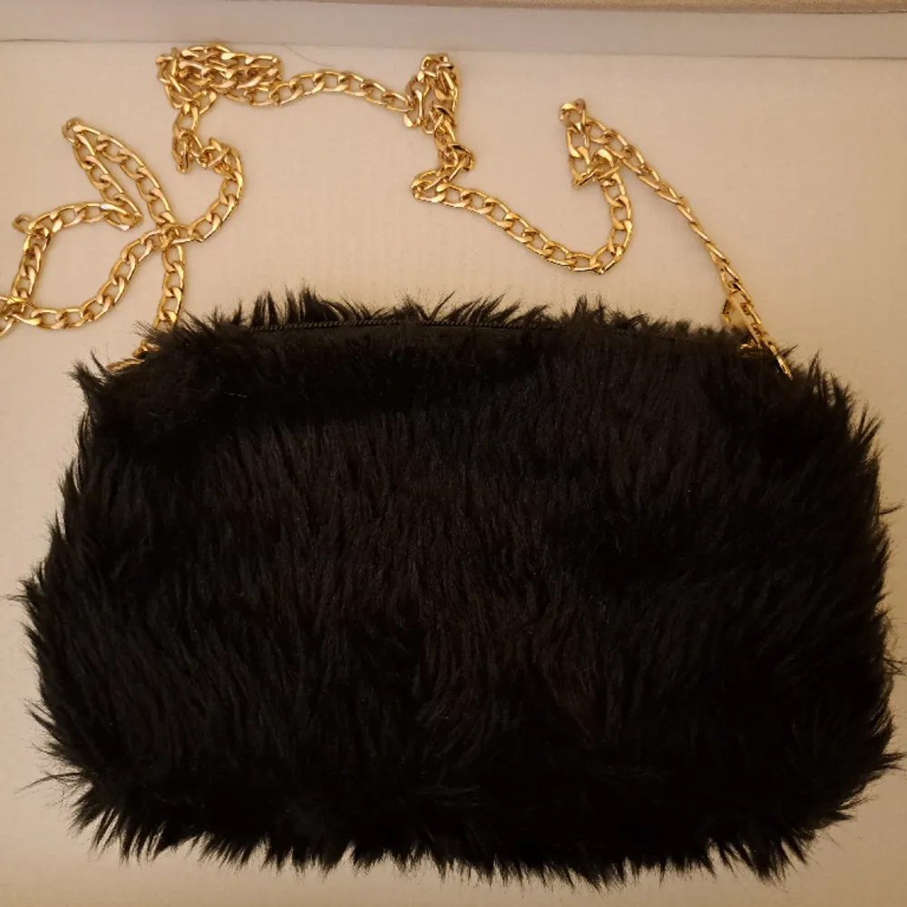 En jättegullig svart fluffig väska med guldigt kedjeband. Användes aldrig så säljer den . Väskor.