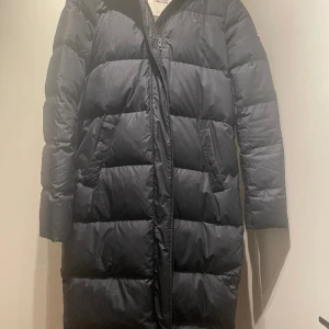 Brun varm lång jacka från Tommy Hilfiger - Brun varm vinterjacka / dunjacka från Tommy Hilfiger i storlek S säljes.  Den har en luva och är ca 100 cm lång.  Jackan är i gott skick.   Finns i djur- och rökfritt hem.  Hämtas på Kungsholmen.  Betalningsmetod Swish. 