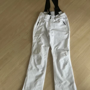 Skidbyxor  - Säljer mina vita skidbyxor från Dare 2b i storlek 34.🩷Varsamt använda och inga större defekter. Längst ner vid benen finns det dragkedja som man kan dra upp för att passa bättre med pjäxor. Även justerbara i midjan. Säljer nu för att jag vill ha svarta. 💞