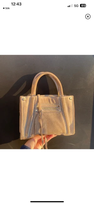 Väska crossbody H&M premium selection i äkta mocka - Jättefin väska från H&M premium selection i äkta mocka (står även inne i väskan). Gulddetaljer. Tecken på användning men annars i fint skick. Grå/beige. Går att göra till crossbody med eget band.