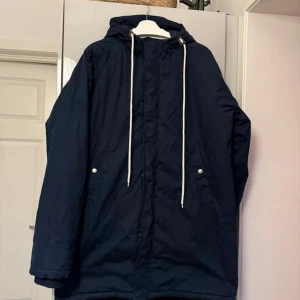 Varm Parkas i fint skick stl XL (Unisex) - Blå Vinterjacka parkasmodell använd ett fåtal gånger Stl XL från Lager 157  Dragsko i midjan som justeras på insidan Supervarm och skön vinterjacka!