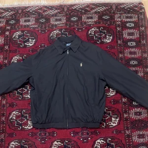Polo Ralph Lauren Harrington Jacka - Säljer nu min Polo Ralph lauren harrington jacka i svart då den är för liten. Jackan har inte använts mycket och är i fint skick. Inga defekter förekommer. Tveka inte att höra av dig vid frågor eller funderingar.