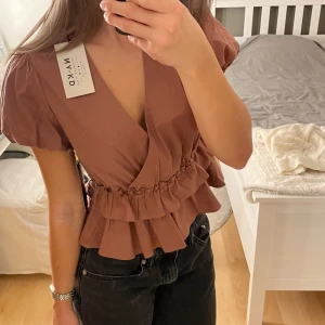Volangtopp från NAKD - Slutsåld volangtopp från NA-KD som är helt oanvänd med lappen kvar. Nypris är 300 kr, mitt pris är 170 kr men går att diskutera. Säljer för att jag beställde dubletter💕