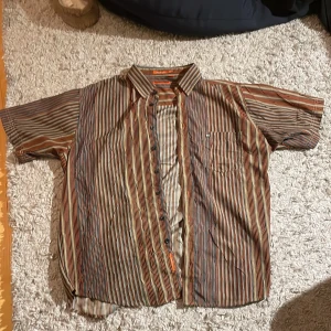 Randig skjorta - Cool randig, kortärmad skjorta från Beyond Retro. Bra skick. Skriv för eventuella frågor! (Tveka inte på att prisförhandla!!)