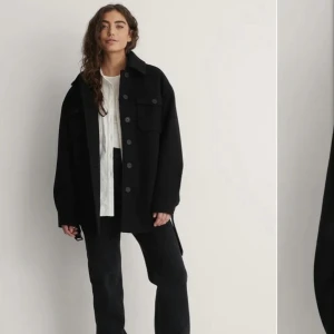 Kappa  - Säljer denna fina svarta kappan från NA-KD. Kappan har bälte och kan knytas runt midjan super fint. Nästan i nyskick 💕kontakta mig för fler bilder!