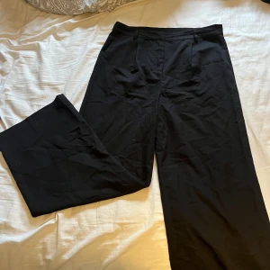 Kostymbyxor  - Svarta kostymbyxor som sitter väldigt fint. Ganska breda i benen men passar till många toppar. Är i väldigt bra skick. Använda vid fåtal tillfällen.