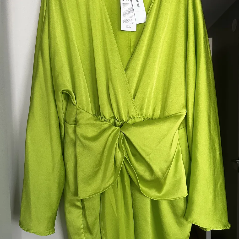 Kort klänning med knytning framtill. Limegrön, glansigt tyg, helt ny oanvänd. Nypris 599. Klänningar.