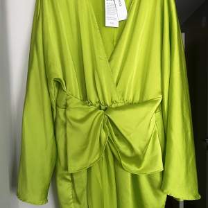 Kort klänning med knytning framtill. Limegrön, glansigt tyg, helt ny oanvänd. Nypris 599