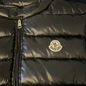 Moncler Väst - Säljer varm och stilren väst från moncler. Västen är i prima skick och har inga skador eller liknande. Den har varit sparsamt använd i drygt ett år till och från men nu vill jag hellre ha pengarna så väljer att sälja detta ögongodis.