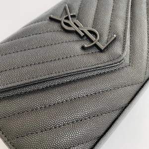 En svart dupe YSL väska med måtten  22,5*14*4cm. Svart kedja.  