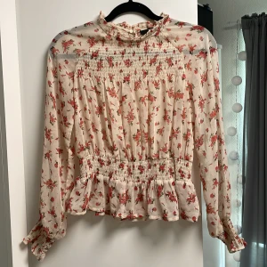 ”Transaparant” blommig blus  - Blommig blus från BikBok i storlek XS. Den är vit/beige transparant med rosa små blommor. Är i ny skick. Passar även för S storlekar.