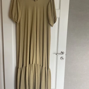 Långklänning  - Fin senapsgul långklänning med knytning i ryggen. Fint fall som slänger vackert när man går. Kommer tyvärr inte till användning hos mig. Jag har inga bilder på.