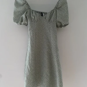 Grön somrig klänning - En grön blommig klänning från h&m använd ett fåtal gånger, fint skick puff ärmar, dragkedja i sidan storlek 32, pris kan diskuteras. 