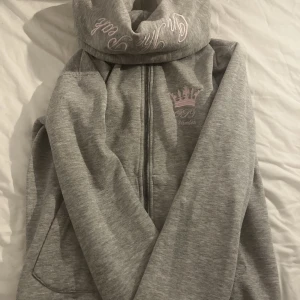 Kofta - Säljer denna koftan. Den har en rosa text på luvan och ett rosa tryck över bröstet. Den har även fått en liten blå fläck som ni ser på bild 2.