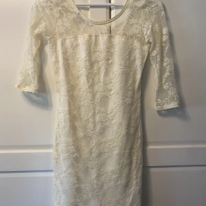Blommig vit klänning.  - Kort blommig vit klänning. Perfekt till skolavslutning/student. Relativt kort och något lägre i ryggen. Spets men inte genomskinlig tack vare underklänning. Passar XXS & XS