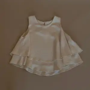 Flowy Silk Tank with Double Skirted Hem. Single Button Closure in Back. Made with Deadstock Designer Heavy Silk Fabric. Excellent Condition. Model is 160cm (5”3) and generally fits XS/S.   40 CM/ 15.7 IN Length 28 CM/ 11 IN Shoulders 76 CM/ 29.9 IN Chest