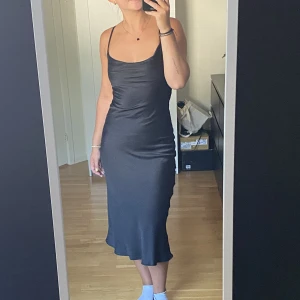 Satinklänning - Svart satinklänning vera Moda, endast använd en gång! Sitter väldigt fint och bekvämt! Korsade band i ryggen och finns dragkedja i ryggen så man lätt får på sig den