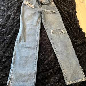 Mellanblå jeans med revor framtill. Inköpta förra året men aldrig använda pga fel storlek. Liten slits nertill ca 8 cm.  Mycket fint skick!  
