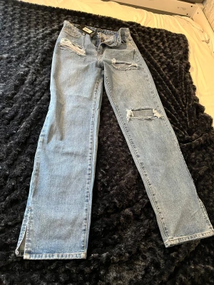 Prettylittlething - Mellanblå jeans med revor framtill. Inköpta förra året men aldrig använda pga fel storlek. Liten slits nertill ca 8 cm.  Mycket fint skick!  