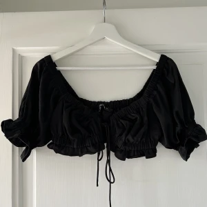 Topp - Svart kort topp i satin material! Använd endast en kväll så den är helt som ny! 