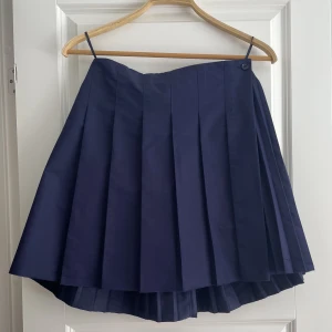 Kjol med pressveck - Marinblå omlottkjol med pressveck från COS. Sparsamt använd 