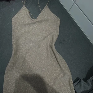 Klänning  - En super fin champagne färgad glitter klänning. Med korsad axelband och är väldigt stretchig. Passar xs & s