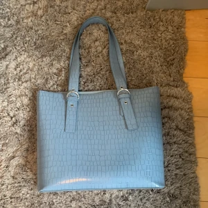 Blå handväska  - Säljer denna blåa handväskan, andvänd max 4 gånger. Den är ifrån H&M. Man får plats med mycket i den! Ungefär 33x20 cm