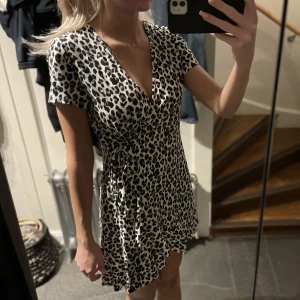 Klänning med knytning - Klänning med svartvitt leopardmönster. Storlek 44 men då den knyts kan storleken anpassas och den passar även mig med storlek S. Bra skick, nästan aldrig använd.
