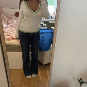 Vit stickad tröja  - Vit stickad tröja med gröna gulliga detaljer och v-ringning 