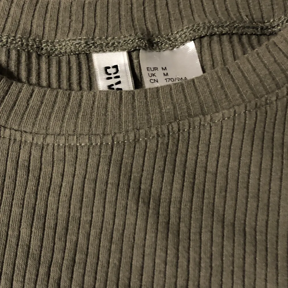 Ribbad militär/oliv grön croptop från H&M, säljs inte längre vad jag kan se, inprincip oanvänd/använd cirka 2 gånger. Stretchigt tyg & passar M-S jättebra, sjukt fint färg, sista bilden är tröjan på 🫶 går precis över naveln på mig! hör av dig vid frågor ❤️. Toppar.