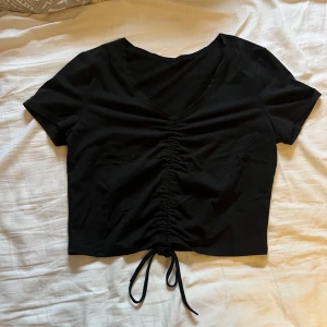Topp med snörning  - En fin, svart topp med snörning i mitten där du kan justera hur högt du vill att tröjan ska sitta. Är i bra skick och väldigt fin men kommer tyvärr inte till användning längre☺️