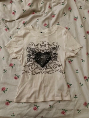 Y2k t shirt med tryck - En fin t shirt som sitter tajt på överkroppen. Xxs men passar också xs o möjligen s. Skit snygg med ett par lågmidhade jeans!!! Tar enbart emot Swish för tillfället för bank id funkar inte!