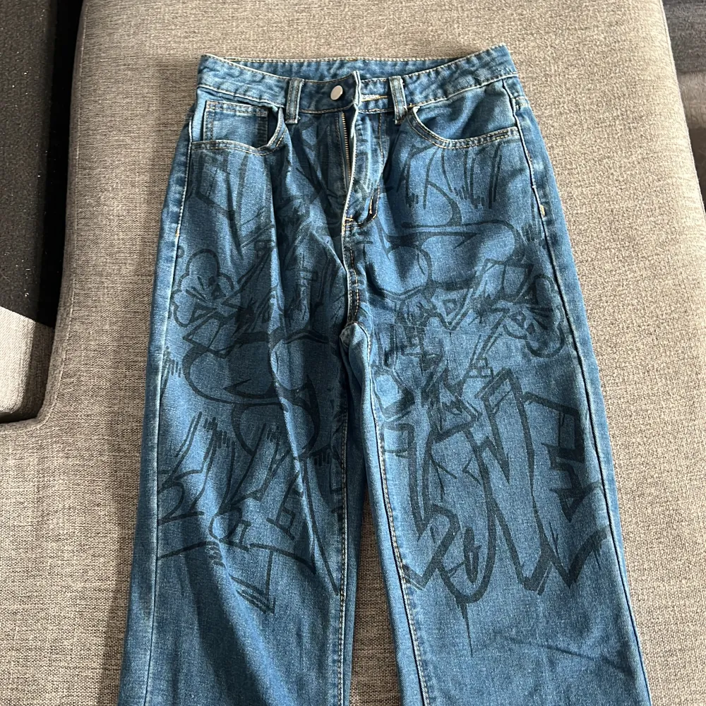 Jeans med graffiti mönster på övre delen av byxorna. Använt ett fåtal gånger så är i bra skick. Är storlek xs men passar som s. . Jeans & Byxor.