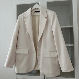 Vit kavaj - En jättefin vit/gräddvit kavaj i satinmaterial från GinaTricot, rak och något Oversized i modellen🌸 Som nyskick då den är väldigt sparsamt använd! Strl: 38🌸 (sålt en i 36 innan, säljer denna åt min syster)