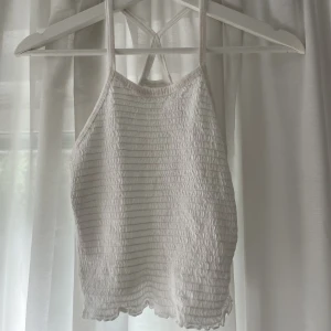 Smocked topp - Fin vit smocked topp med kryss-rygg. Från Lindex. Använd 2 ggr. 