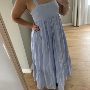 Långklänning med fina detaljer  - Fin blå/lila långklänning med rosa mönster. Det är även en underklänning till så den känns lyxig i modellen och axelbanden blir en fin detalj.