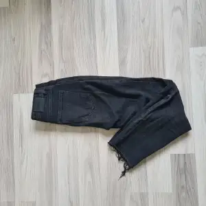 Ett par svarta jeans med slitningar nertill