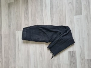Jeans - Ett par svarta jeans med slitningar nertill