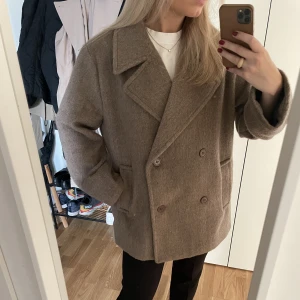 Kort kappa NAKD - Kort beige/brun kappa från NAKD och Moa Mattssons kollektion. Den är hur fin som helst men används tyvärr inte. Storlek 32 men passar 32-38 beroende på vad man vill ha för passform. Köparen står för frakten 🤎