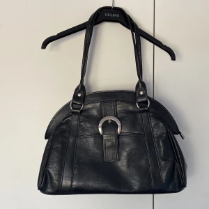 Svart handväska - En rymlig svart handväska i läder med silverdetaljer. Har ett fack inuti och stänga med dragkedja! Perfekt för en liten dator eller anteckningsböcker till skolan🖤🖤🖤